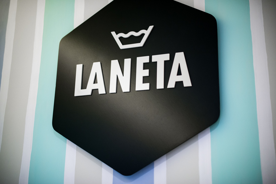 Rètol de la marca La Neta en la decoració interior de la bugaderia, logo sobre paret pintada a ratlles de pijama. LANETA lavandería, laundrette